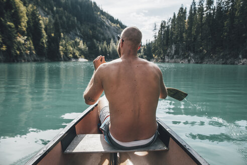 Canada, British Columbia, barechested man in canoe on Kinbasket Lake - GUSF00454