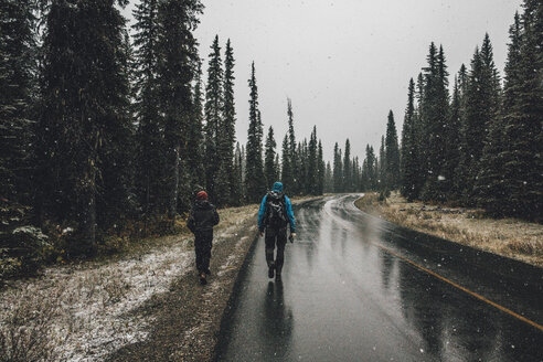 Kanada, Britisch-Kolumbien, Yoho-Nationalpark, zwei Männer beim Wandern auf der Yoho Valley Road bei Schneefall - GUSF00469
