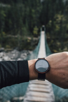 Männerhand mit Uhr vor einer schwingenden Brücke - GUSF00475