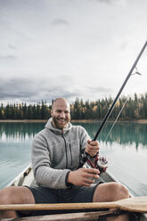 Canada, British Columbia, portrait of happy man fishing in canoe on Boya Lake - GUSF00502