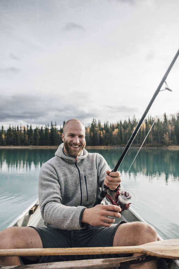 Canada, British Columbia, portrait of happy man fishing in canoe