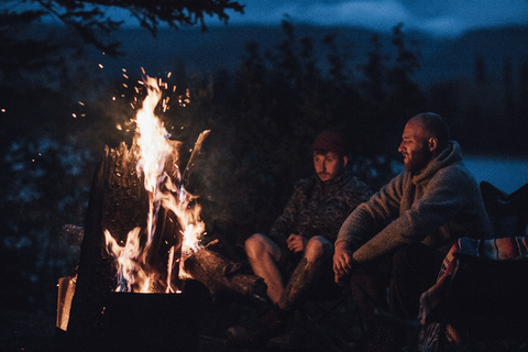 Kanada, British Columbia, zwei Männer sitzen nachts am Lagerfeuer am Boya Lake, lizenzfreies Stockfoto