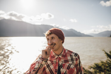 Canada, British Columbia, portrait of smiling man eating a cookie - GUSF00515