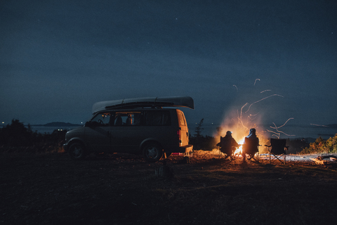 Canada, British Columbia, Prince Rupert, two men sitting at camp fire at minivan at night stock photo