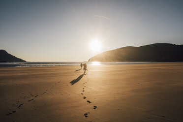 Kanada, British Columbia, Vancouver Island, zwei Männer, die bei Sonnenuntergang am Strand der San Josef Bay spazieren gehen - GUSF00527