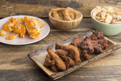 Typisch amerikanisches Essen, Kartoffeln mit Käse und Speck, gebratene Zwiebelringe und Chicken Wings, lizenzfreies Stockfoto