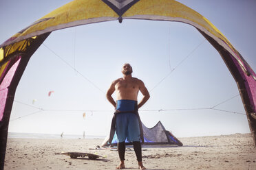 Mann bereitet sich auf das Kiteboarding am sonnigen Strand vor - CAIF05870