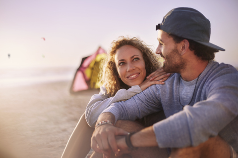 Paar sitzt und spricht am Strand, lizenzfreies Stockfoto