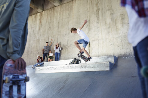 Freunde beobachten und bejubeln einen Teenager beim Skateboardfahren im Skatepark - CAIF05932