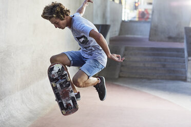 Teenage boy flipping skateboard at skate park - CAIF05941