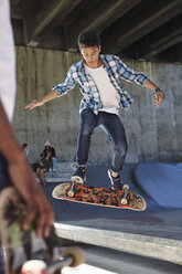 Konzentrierter Teenager, der sein Skateboard im Skatepark umdreht - CAIF05951