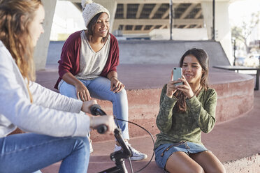 Teenager-Mädchen benutzen Fotohandy im Skatepark - CAIF05954