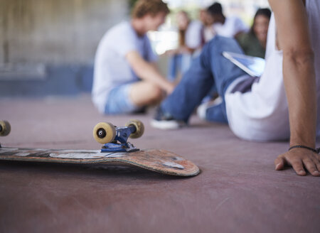 Skateboard auf dem Kopf neben Teenager-Freunden, die im Skatepark abhängen - CAIF05957