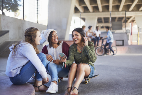 Teenager-Mädchen auf dem Skateboard SMS schreiben und im Skatepark abhängen, lizenzfreies Stockfoto