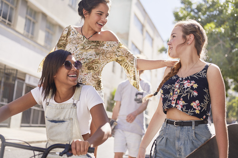 Teenager-Mädchen mit BMX-Fahrrad und Skateboard auf sonnigen städtischen Straße, lizenzfreies Stockfoto