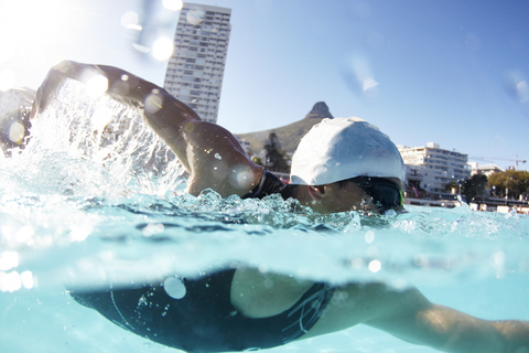 Männlicher Schwimmer, der in einem sonnigen Schwimmbad schwimmt, lizenzfreies Stockfoto