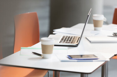 Laptop, coffee and paperwork on table in office - CAIF06035