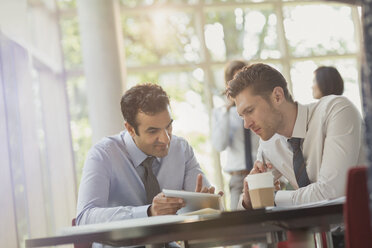 Businessmen using digital tablet at office table - CAIF06040