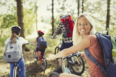 Porträt lächelnde Mutter beim Mountainbiking mit Familie im Wald - CAIF06045