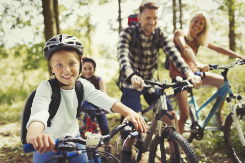 Portrait smiling girl mountain biking with family in woods stock photo