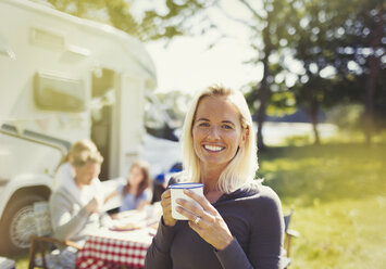 Portrait smiling woman drinking coffee outside sunny motor home - CAIF06049