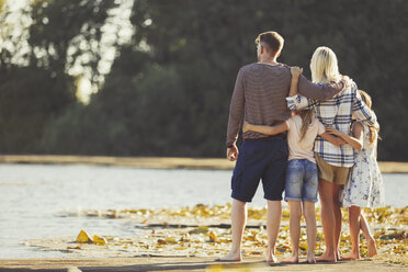 Family hugging at sunny lakeside - CAIF06060