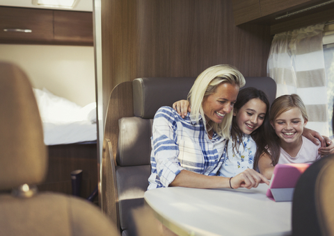 Lächelnde Mutter und Töchter benutzen ein digitales Tablet im Wohnmobil, lizenzfreies Stockfoto