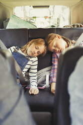 Tired sisters sleeping in back seat of car - CAIF06074