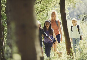 Mother and daughters hiking in sunny woods - CAIF06076