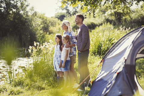 Familie auf sonnigem Campingplatz am Seeufer mit Blick in die Ferne, lizenzfreies Stockfoto