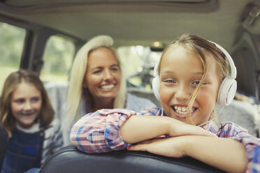 Portrait lächelndes Mädchen mit Kopfhörern auf dem Rücksitz eines Autos - CAIF06086