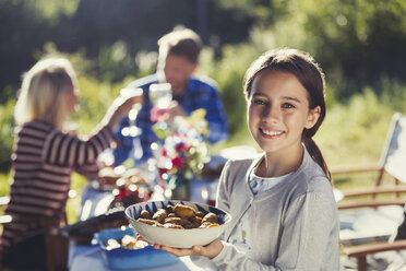 Porträt lächelnd Mädchen serviert Essen im sonnigen Garten Partei Terrasse Tisch - CAIF06087