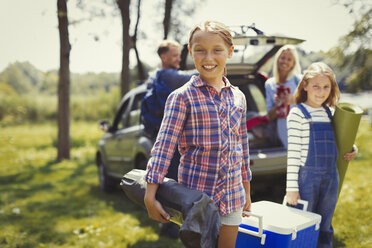 Portrait smiling family unloading camping equipment from car - CAIF06089