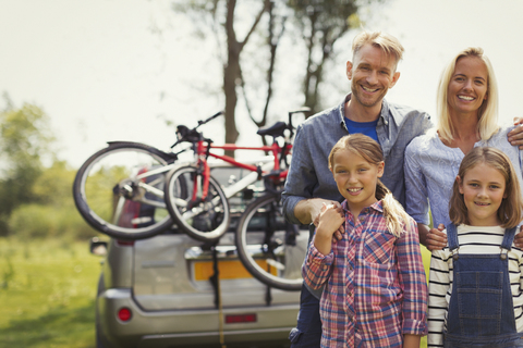 Porträt lächelnde Familie in der Nähe von Auto mit Mountainbikes, lizenzfreies Stockfoto