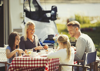 Familie genießt das Frühstück am Tisch vor dem sonnigen Wohnmobil - CAIF06104