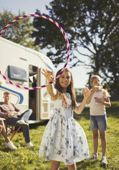 Portrait playful girl spinning plastic hoop outside sunny motor home - CAIF06111