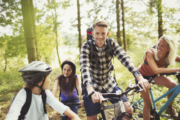 Smiling family mountain biking in woods - CAIF06112