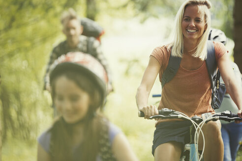 Lächelnde Familie beim Mountainbiken im Wald - CAIF06113