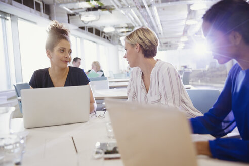 Businesswomen talking, working at laptops in office meeting - CAIF06148