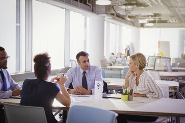 Business people talking at table in shared workspace - CAIF06158