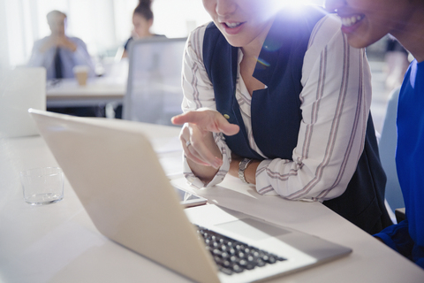 Geschäftsfrauen im Gespräch, arbeiten am Laptop in einer Bürobesprechung, lizenzfreies Stockfoto