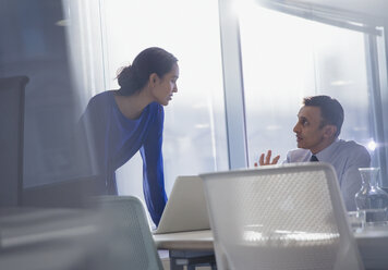 Businessman and businesswoman using laptop, talking in office - CAIF06184