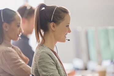 Lächelnde Telefonverkäuferin mit Headset, die im Büro telefoniert - CAIF06254