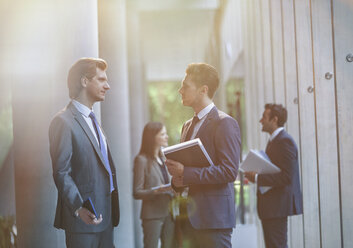 Businessmen talking in office lobby - CAIF06256