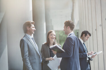 Business people talking and laughing in sunny office lobby - CAIF06267