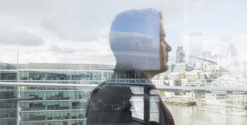 Nachdenklicher Geschäftsmann mit Blick auf die Stadt vom Balkon aus, London, UK - CAIF06279