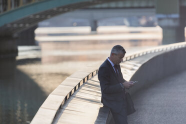 Geschäftsmann, der mit seinem Handy am städtischen Hafen eine SMS schreibt - CAIF06281