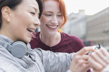 Smiling female runners checking smart watch - CAIF06332