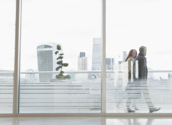 Geschäftsmann und Geschäftsfrau zu Fuß auf städtischen Hochhaus Balkon mit Blick auf die Stadt - CAIF06342