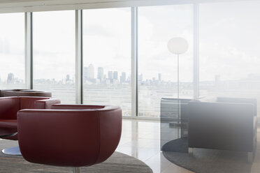 Leather chairs and sofa in urban modern office lounge with city view - CAIF06357